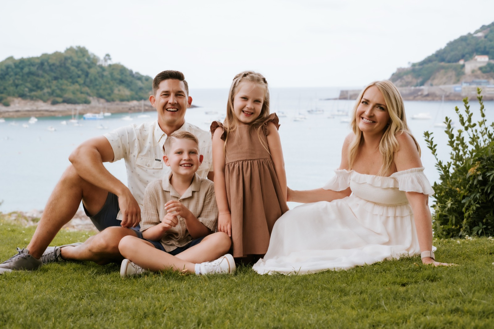 Adam and Amber Wong with their family, sitting in the grass in San Sebastián, Spain